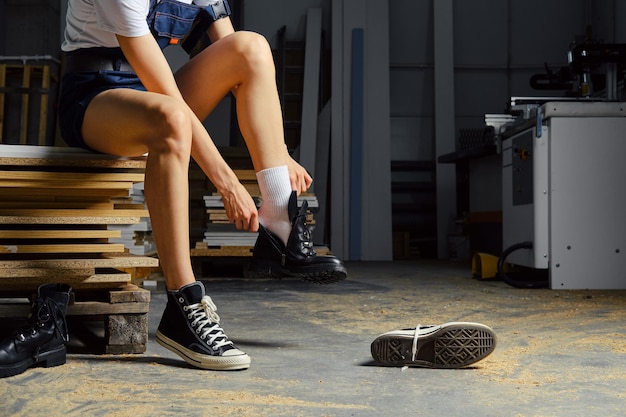 Unrecognisable woman changing footwear in carpenter shop