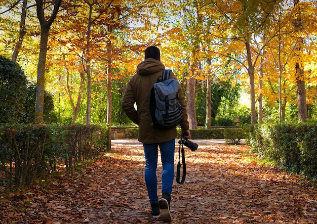 Unrecognizable boy walking with camera in fall