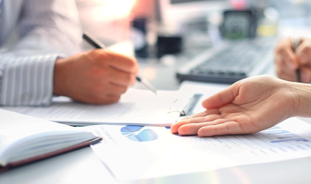 Unrecognizable business person analyzing graphs and taking notes