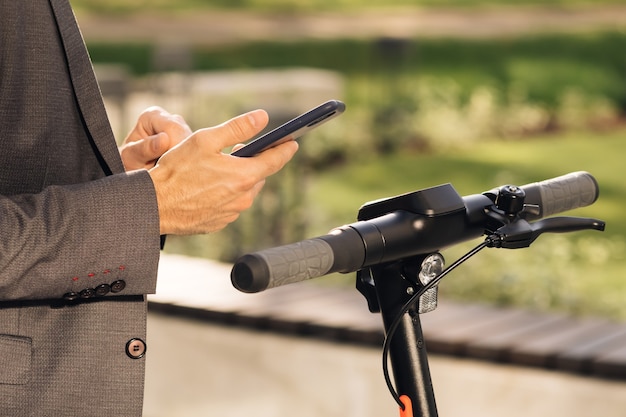 Unrecognizable businessman take rent electric kick scooter nfc contactless locker on bike bicycle