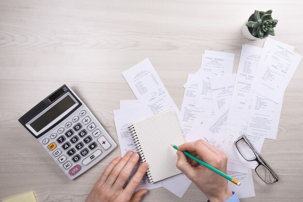 Unrecognizable businessman using calculator on desk office and writing make note with calculate about cost at home office. finance accounting concept. tax , shopping, cost management.