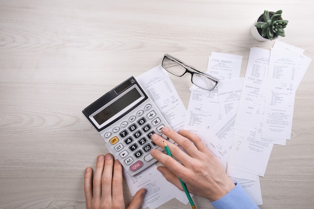 Unrecognizable businessman using calculator on desk office and writing make note with calculate about cost at home office.