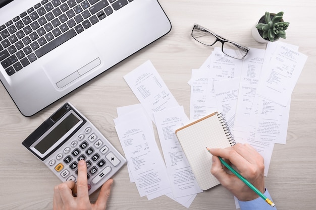 Unrecognizable businessman using calculator on desk office and writing make note with calculate about cost at home office