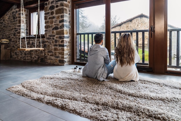 Unrecognizable caucasian couple relaxing looking by the window in the attic of their home