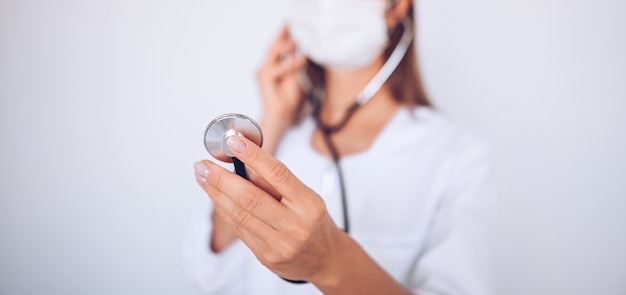 Unrecognizable doctor nurse wearing protective mask and stethoscope check breathing, corona virus prevention, hygiene to stop spreading coronavirus. Avoid contaminating Corona virus Covid-19 concept