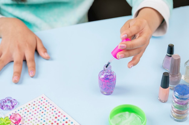 Unrecognizable girl paints her nails with varnish at home