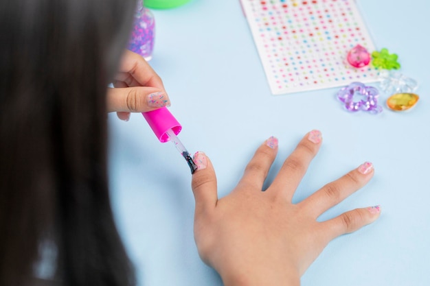 Unrecognizable girl paints her nails with varnish at home