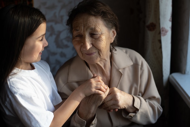 Unrecognizable grandmother and her granddaughter holding hands.