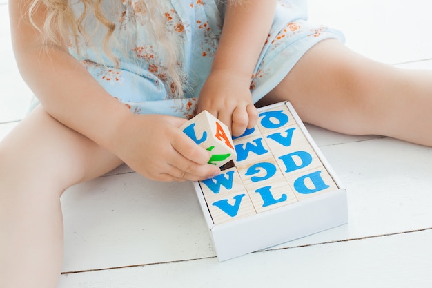 Unrecognizable little girl playing with abc cubes indoors