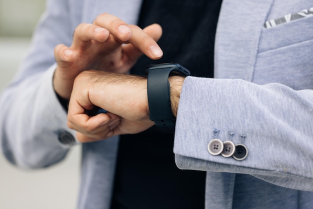 Unrecognizable male hands using smart watch businessman uses a smartwatch on his hand and keeps