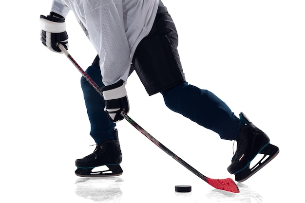 Unrecognizable male hockey player with the stick on ice court and white background. Sportsman wearing equipment and helmet practicing. Concept of sport, healthy lifestyle, motion, action. Close up.