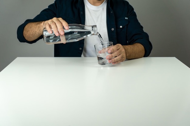 Unrecognizable man pouring water into a glass to hydrate himself hydration and wellness concept