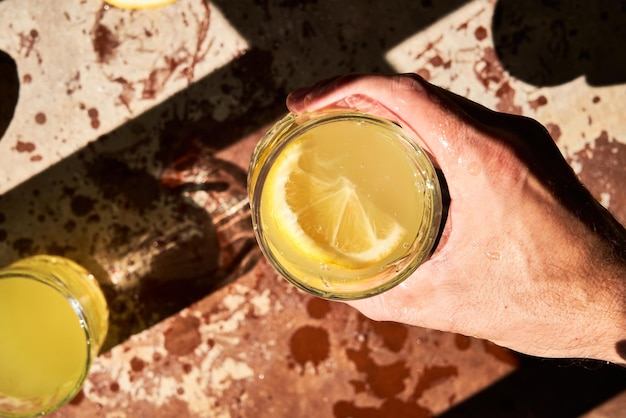 Unrecognizable man's hand holding a glass of fresh lemonade. Top view