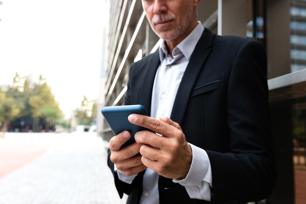 Unrecognizable man using mobile phone outside the office Copy space Selective focus on hands