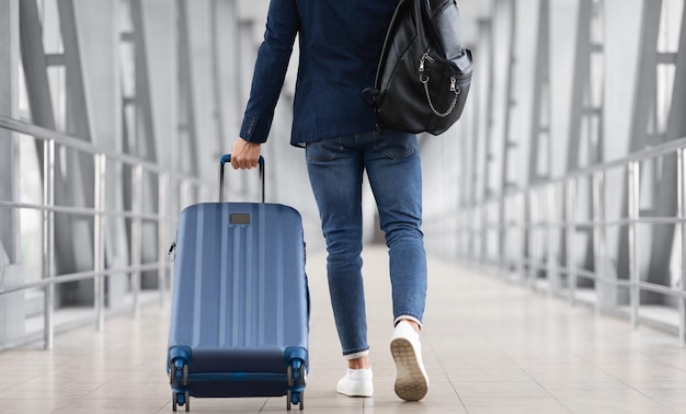 Unrecognizable Man With Bag And Suitcase Walking In Airport Rear View