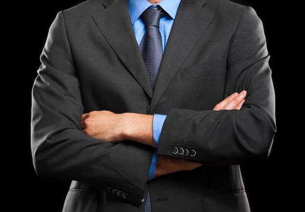 Unrecognizable man with folded arms on dark background