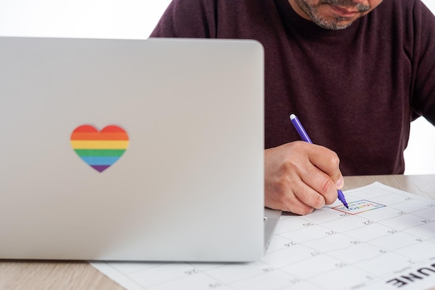 Unrecognizable mature man marking on a calendar the date of the International LGBTQ Pride Day