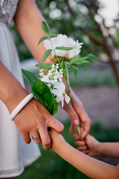 Unrecognizable mom and daughter holding hands in blossom spring garden Happy woman and child, Wearing white dress outdoors, Spring season is coming. Mothers day holiday concept