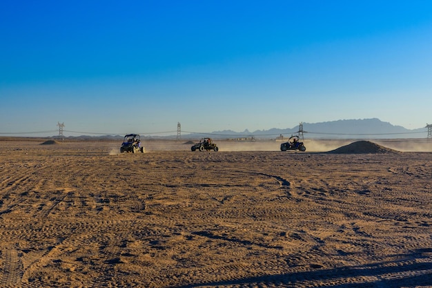 Unrecognizable people driving buggies during safari trip at sunset in Arabian desert not far from the Hurghada city Egypt