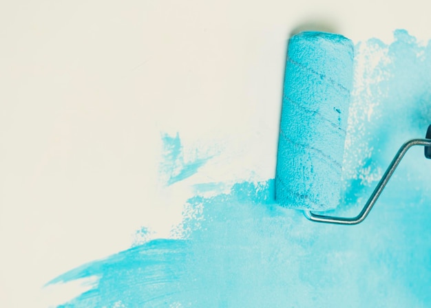 Unrecognizable person applying blue paint on wall Female hand with roller painting wall Concept of repair work and improvement of housing conditions