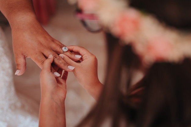 Unrecognizable person putting a ring to the bride on her wedding day