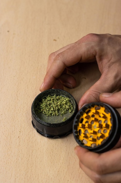 Unrecognizable person using a marihuana grinder to shred the buds before rolling a joint