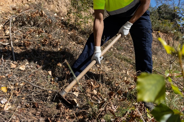 Unrecognizable person with gloves removing soil with a hoe, close up view