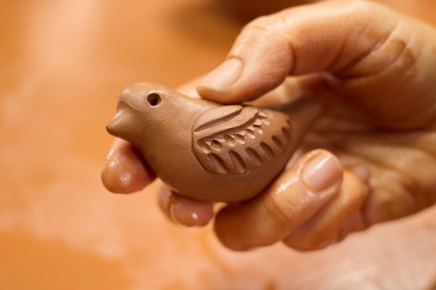 Photo unrecognizable potter master holding bird sculpture from clay clay in hand