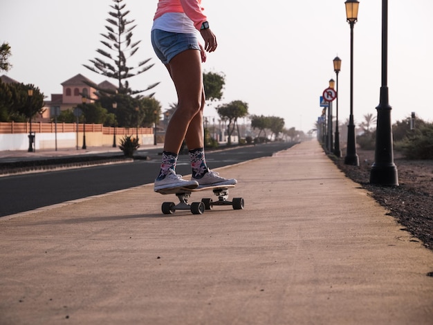 Unrecognizable skater woman from behind skating down the street