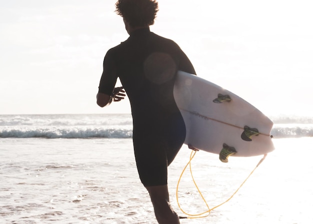 Unrecognizable surfer running to the waves