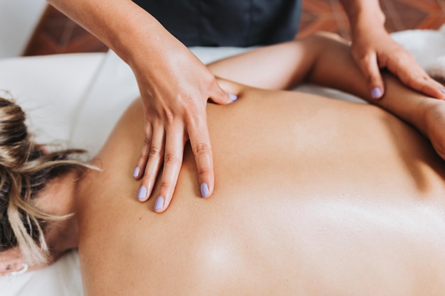 Unrecognizable therapist making back and scapula massage to a female patient with back pain