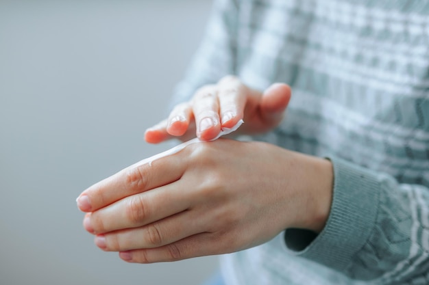 Unrecognizable woman applying natural moisturizer cream to her hands close up