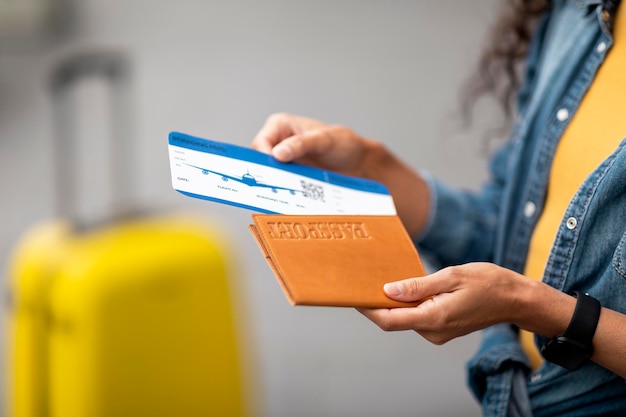 Unrecognizable woman in casual outfit holding passport and flight tickets