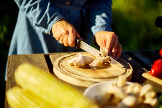 Unrecognizable woman cutting fresh mushroom vegetables on wooden board