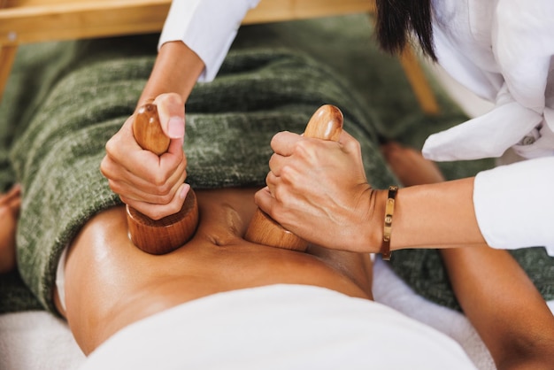 An unrecognizable woman getting anti cellulite maderotherapy massage with wooden cup at the beauty salon.