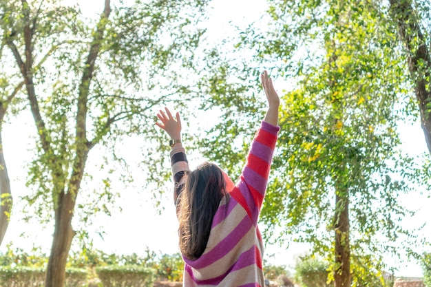 Unrecognizable woman on her back in nature raising her arms concept of freedom relaxation tranquility