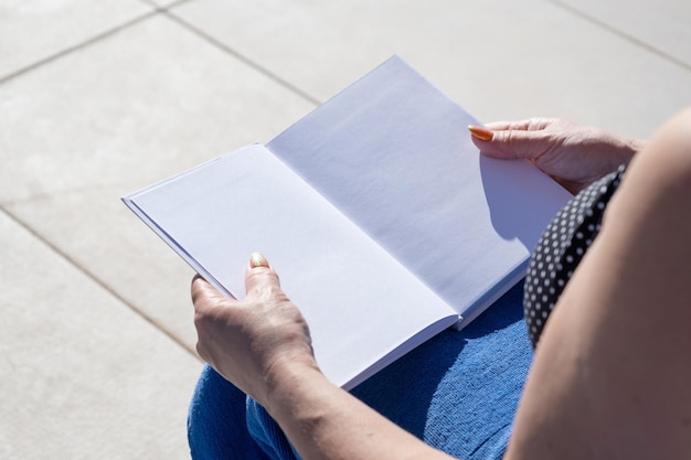 unrecognizable woman holding blank book for mockup design sitting by the swimming pool