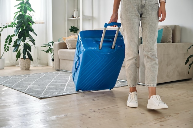 Unrecognizable woman leaving home with a suitcase going on a trip or vacation