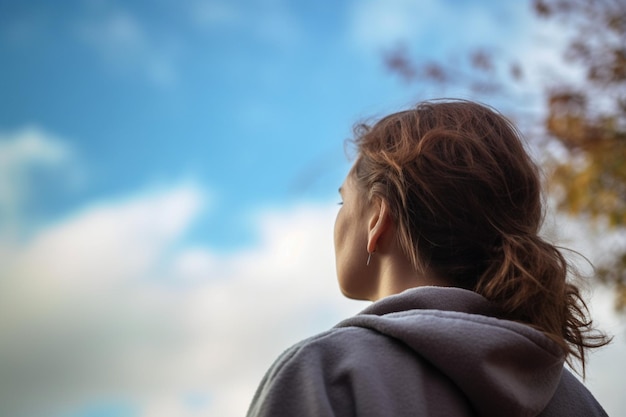 unrecognizable Woman looking up into the sky and thinking about her future rear view