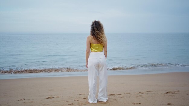 Unrecognizable woman standing beach looking picturesque ocean waves alone