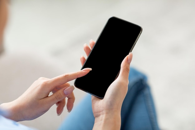 Unrecognizable woman using smartphone with blank screen mockup