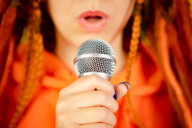 Unrecognizable woman with dreadlocks singing into microphone Full frame Body part of female with mic Selective focus Close up