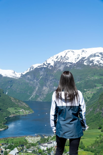 Unrecognizable woman with an incredible view of the Geirangerfjord in the background with the snowy mountains and a sunny day