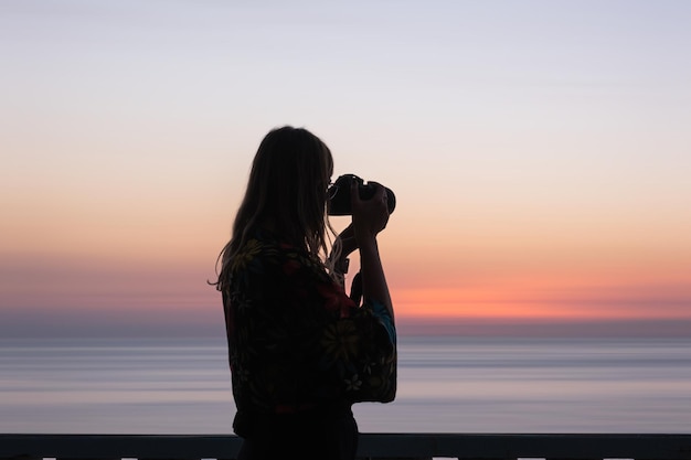 Unrecognizable woman with photo camera in sunset