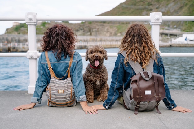 Unrecognizable women with brown water dog. Horizontal view of women traveling with pet. Lifestyle with animals outdoors.