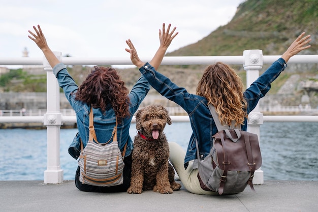 Unrecognizable women with brown water dog. Horizontal view of women traveling with pet. Lifestyle with animals outdoors.