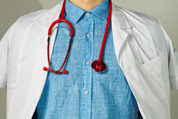 Unrecognizable young man doctor standing over light background