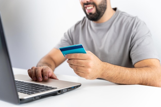 Unrecognizable young man with computer and holding card to shop online from home concept shopping black friday cyber monday sales christmas