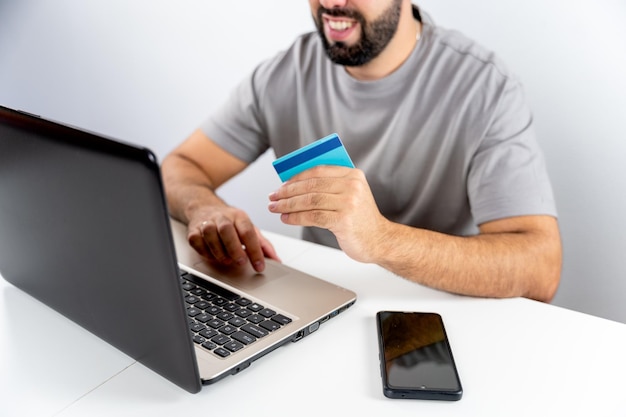 Unrecognizable young man with computer and holding card to shop online from home concept shopping black friday cyber monday sales christmas