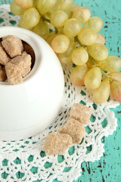 Unrefined sugar in white sugar bowl on wooden background